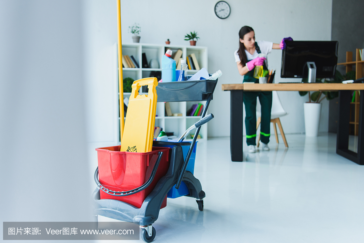年輕女清潔工用各種清潔設(shè)備清潔辦公室